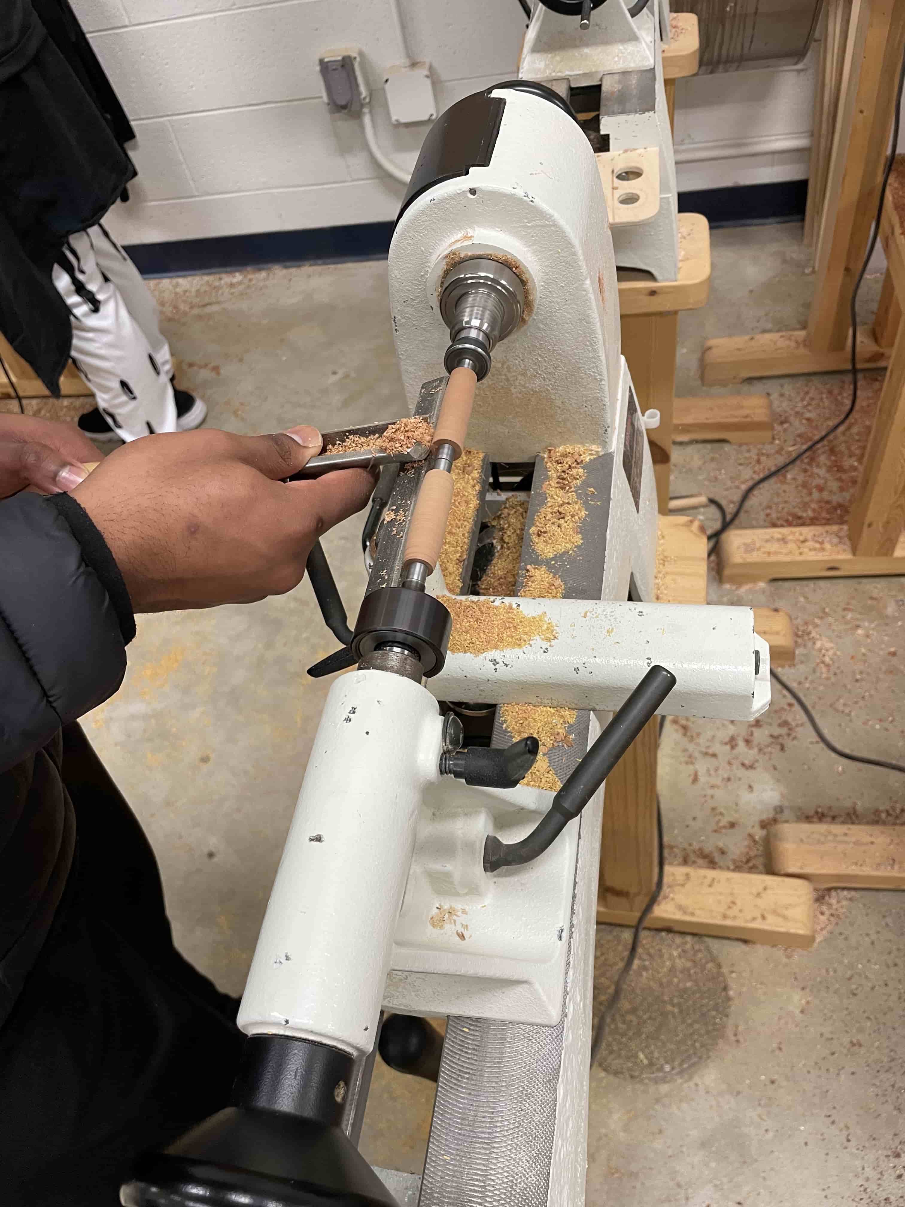 student turning wooden pen on the lathe